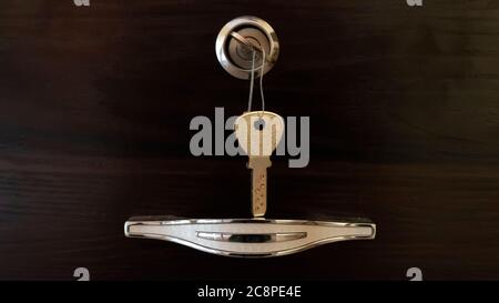 a close view of chrome handle with key lock isolated on wooden background Stock Photo