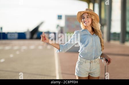 Female tourist trying to catch taxi, arriving at airport Stock Photo