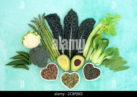 Healthy heart food with green vegetables, nuts, spice & herb selection. Health foods high in fibre, antioxidants, vitamins, omega 3 and protein. Suppo Stock Photo