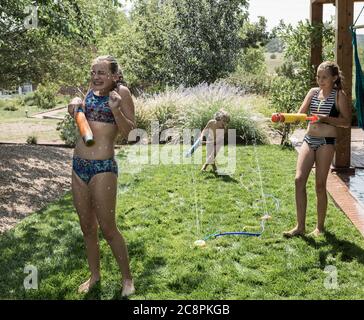 children spraying each other with water hose Stock Photo