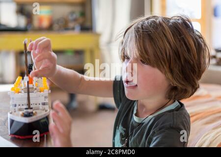 5 year old boy playing with his toy boat at home Stock Photo