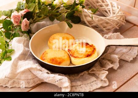 Baked fried cottage cheese pancakes in a white vintage pan, shabby table Stock Photo