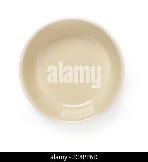 Empty beige ceramic bowl or ramekin isolated on a white background. Empty crockery for food design. Clay, ceramics or porcelain tableware. Top view. Stock Photo