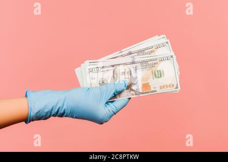 Profile side view closeup of human hand in blue surgical gloves holding and showing fan of american dollar money in hand. indoor, studio shot, isolate Stock Photo