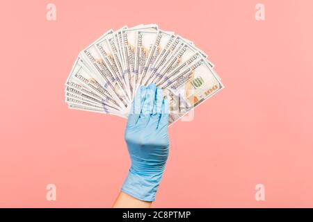 Profile side view closeup of human hand in blue surgical gloves holding and showing fan of american dollar money in hand. indoor, studio shot, isolate Stock Photo