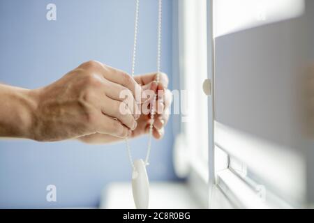 Man testing cassette roller blinds on windows. Stock Photo