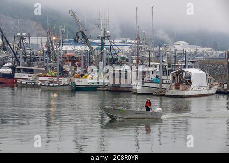 Ketchikan, Alaska - jul 23, 2018 - Small boat sails in front of fishing boats docked on harbor Stock Photo