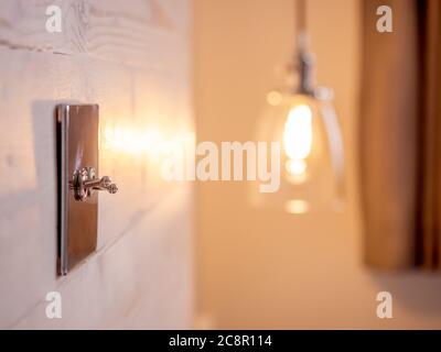 Retro style chrome plated toggle light switches fitted to wooden headboard in bedroom. Stock Photo
