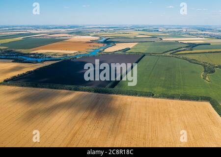 Green and yellow harvest fields aerial view, flight above on drone. Stock Photo