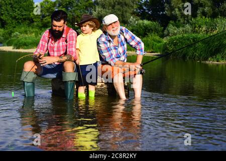 Grandfather, father and son are fly fishing on river. Man in different ages. Stock Photo