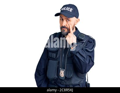 Young handsome man wearing police uniform pointing to the eye watching you gesture, suspicious expression Stock Photo
