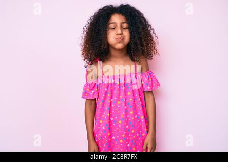 African american child with curly hair wearing casual dress puffing cheeks with funny face. mouth inflated with air, crazy expression. Stock Photo