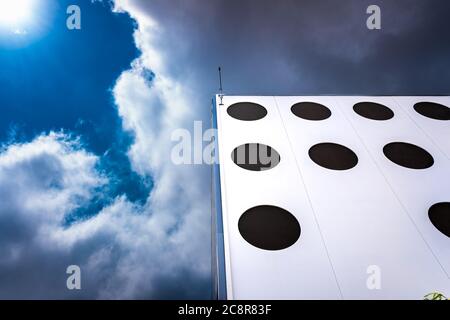 Metal facade with round shapes threatened by rain clouds in the background in the sky. Stock Photo