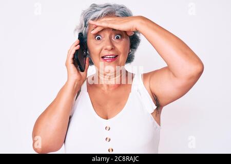 Senior hispanic grey- haired woman having conversation talking on the smartphone stressed and frustrated with hand on head, surprised and angry face Stock Photo