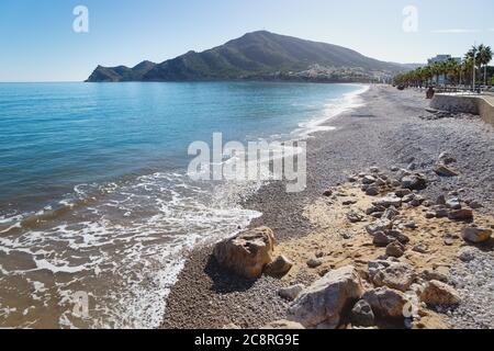 Beach of Albir with turquoise water and view on the promenade aligned with palm trees and mountain, Costa Blanca, Spain Stock Photo