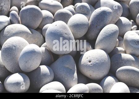 Close up of rounded bright white and grey stones at a sunny beach Stock Photo
