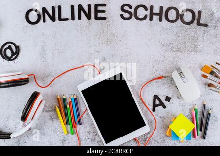 Text online school and tablet with black mockup screen and school supplies on white table. Back to school concept. Stock Photo