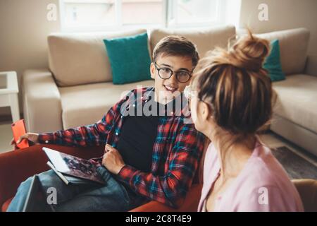 Side view photo of a caucasian couple with eyeglasses working from home at the tablet while discussing Stock Photo