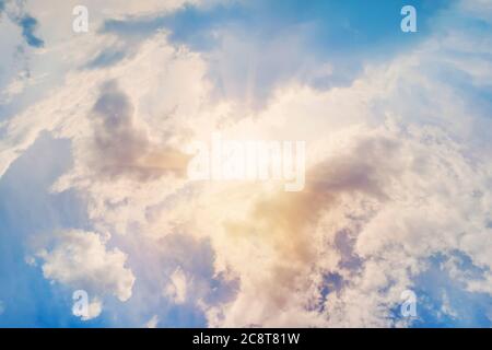 ecrice the rays of the sun shining through the feathery white clouds in the blue sky. Beautiful background. blue sky clouds Stock Photo