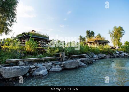 Small log houses for outdoor recreation are located on the river Bank. Hunting ground. Tourist base near water. agrotourism Stock Photo