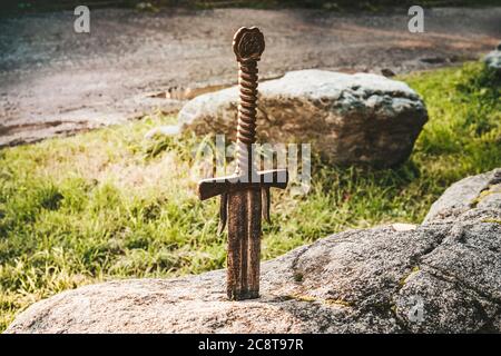 famous sword excalibur of King Arthur stuck in rock. Edged weapons from the legend Pro king Arthur. Stock Photo