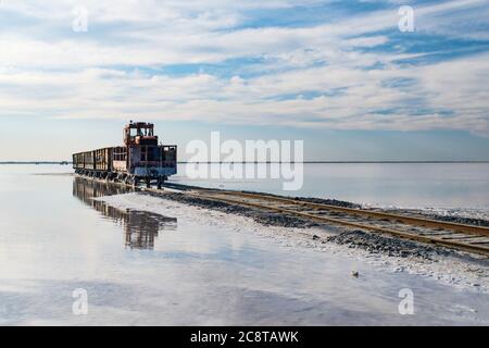 train travels from water. Mined salt in Lake Burlin. Altai. Russia. Bursolith. Old train rides on the railway laid in the water through the salt lake. Stock Photo