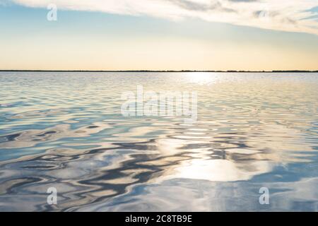 reflected sun rays on sea water. Glare on the water in form of stars. Natural abstract sea water background.