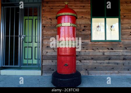 Glenrowan, Victoria. A bright red old Australian postbox stands tall outside a wooden clad building in the historical town of Glenrowan in Victoria's Stock Photo