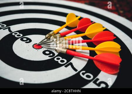 red and yellow dart on target board right frame. yellow and red Darts lie on a black and white target Stock Photo