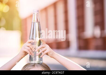 Little girl holding water bottle. Outdoor training. Thirsty. Glass drink Stock Photo