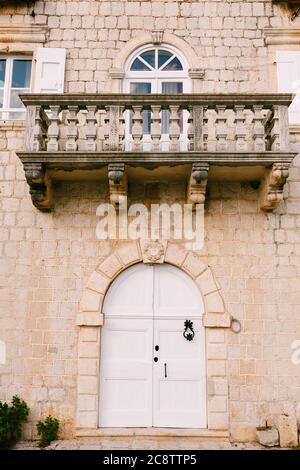 The entrance to the house is from a white door under the balcony. Stock Photo