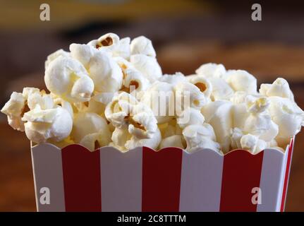 Popcorn in striped retro red and white cardboard box for cinema on wooden table Stock Photo
