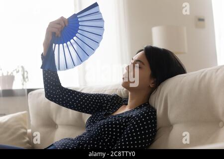 Unwell Asian girl feel overheated wave using hand fan Stock Photo