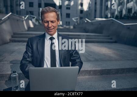 Joyful businessman using laptop on the street Stock Photo