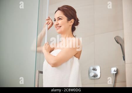 Contented lady standing in a shower booth Stock Photo