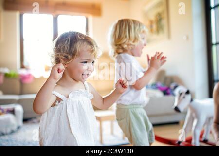 Portrait of small boy and girl playing indoors at home. Stock Photo