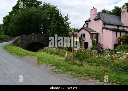A pretty cottage for sale alongside the Monmouthshire & Brecon Canal in Brecon. Old stone bridge crossing canal. Taff Trail signpost. Stock Photo