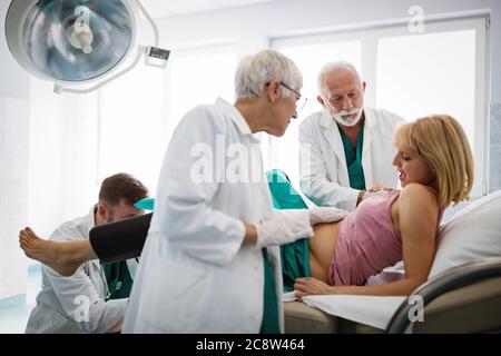 In the hospital woman in labor pushes to give birth, obstetricians assisting Stock Photo
