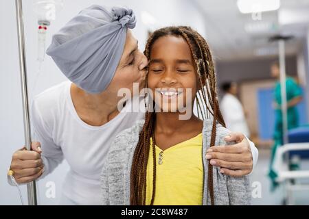 Sick woman with cancer hugging her young grandchild in hospital. Family support concept. Stock Photo