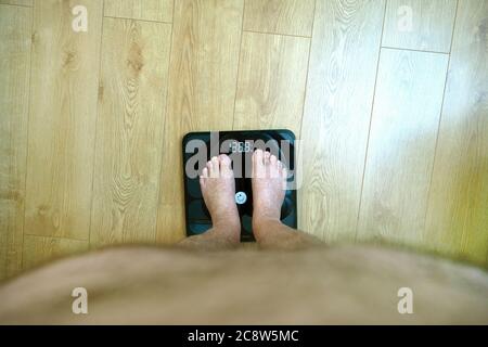 Obese man's point of view looking at his feet on the weighing scales Stock Photo