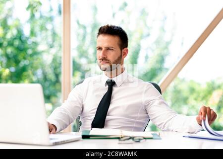 Shot of handsome businessman looking thoughtful while working on laptop at the office. Stock Photo