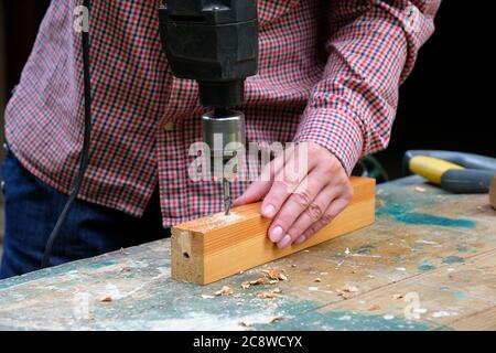 Close-up of female carpenter drilling wooden plank to make hole. DIY, woodwork concept. Stock Photo