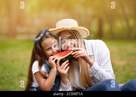 Happy Mother And Daughter Eating Watermelon On Picnic In Park Stock Photo