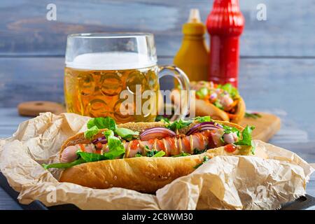 Homemade hot dog with sausage, salad, carrot, cucumber and tomato on wooden background Stock Photo