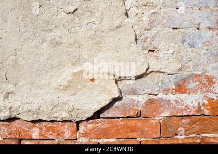 Empty old brick wall texture. Shabby facade of a building with damaged plaster. Stock Photo