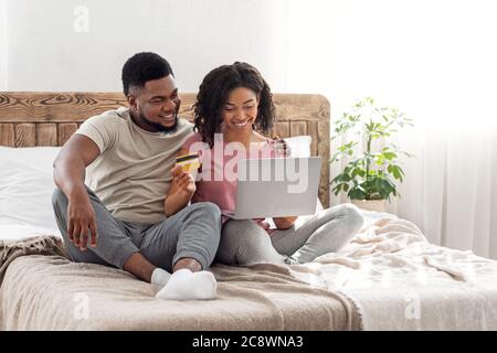 Black couple shopaholics making purchases online, using laptop Stock Photo