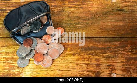 Open black leather pocket wallet full of various coins. Financial crisis, poverty, lack of money. On wooden background or table. Flat lay. Top view. C Stock Photo