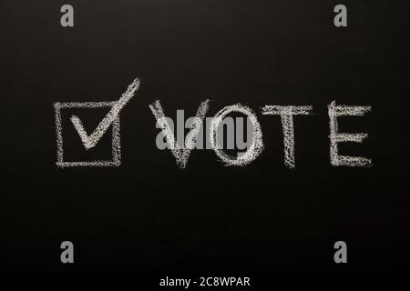 Vote tick on chalkboard, black background, elections 2020 Stock Photo