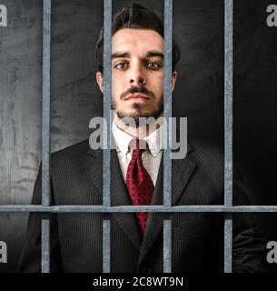 young businessman in jail on dark background Stock Photo
