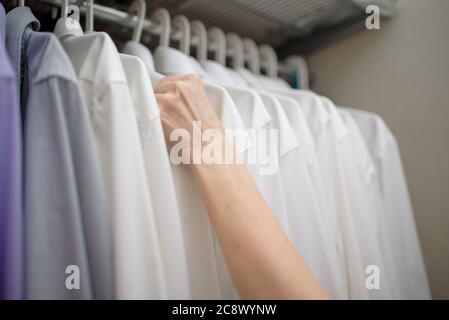 white men's shirts hang on the shoulders in the closet Stock Photo